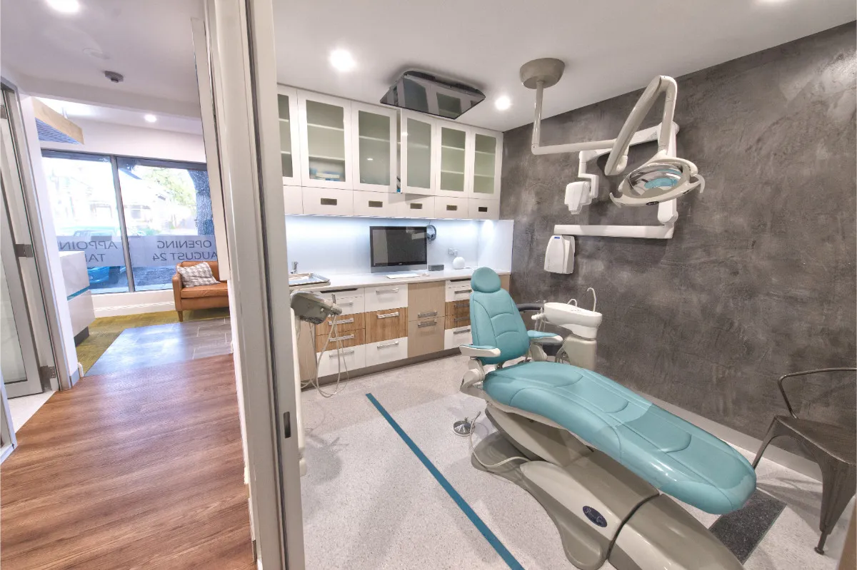 Second dental surgery with teal-upholstered chair, timber-and-white cabinets, and concrete-finish wall.