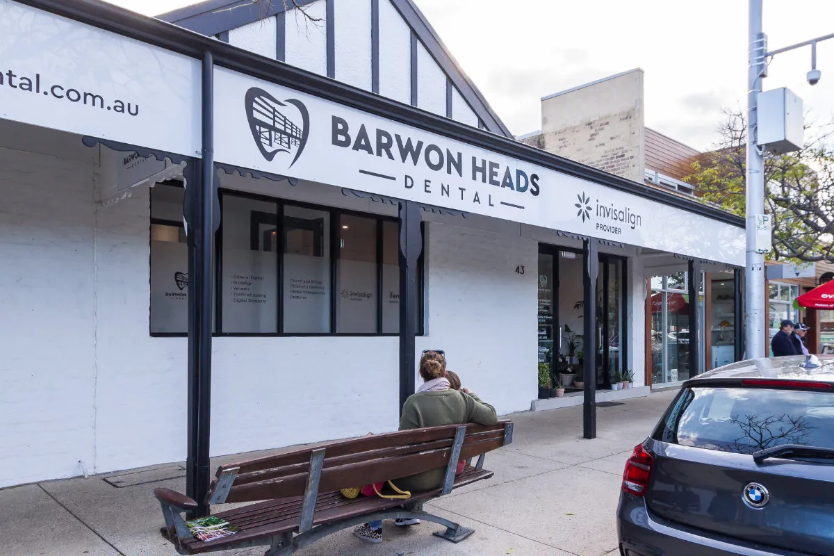 Two patrons on a footpath bench outside the Barwon Heads Dental shopfront.