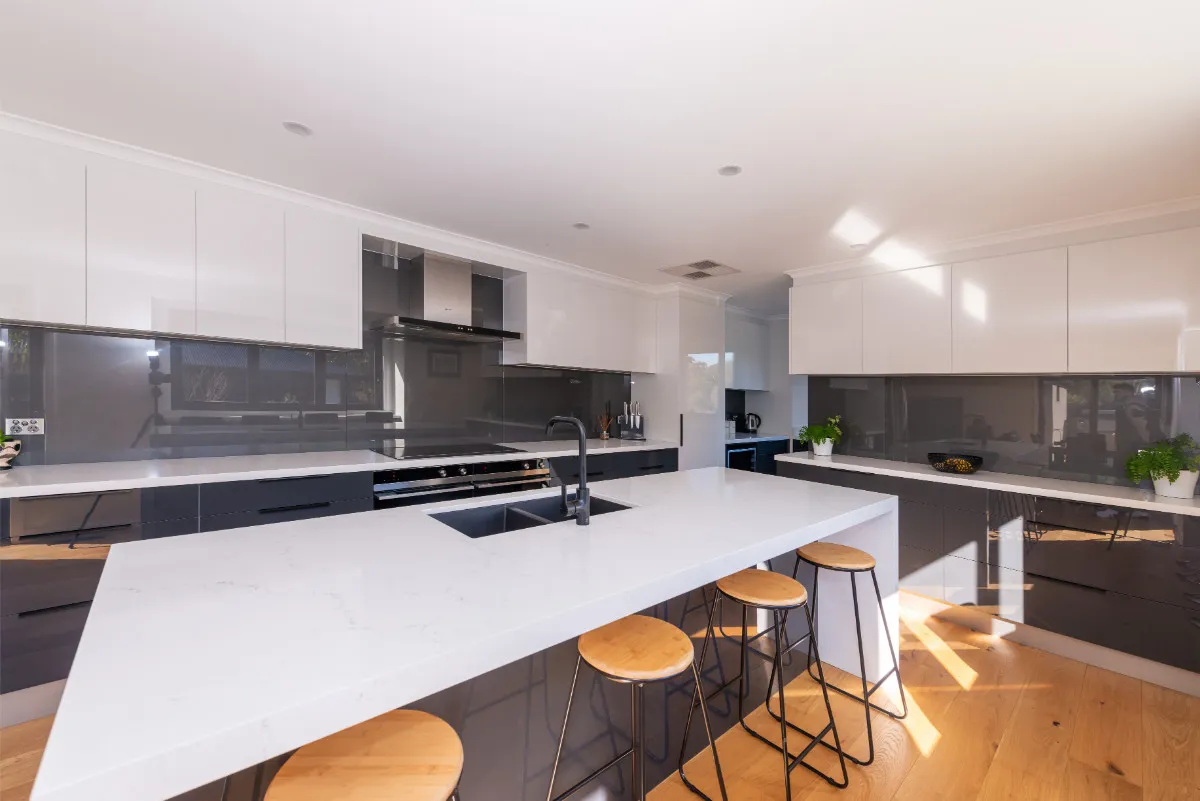 Eltham renovation kitchen with white stone island, charcoal cabinets, and timber stools.