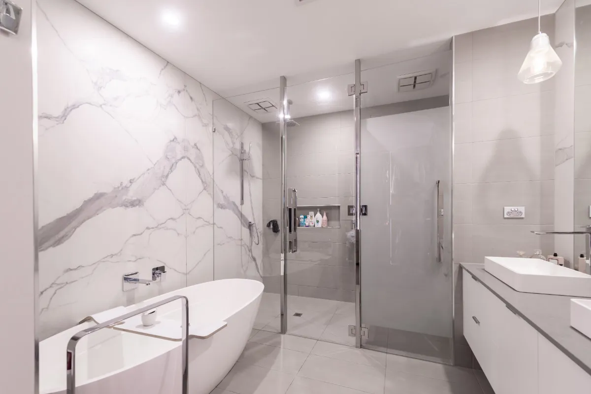 Master bathroom with marble-look feature wall, freestanding tub, walk-in shower, and twin vanities.