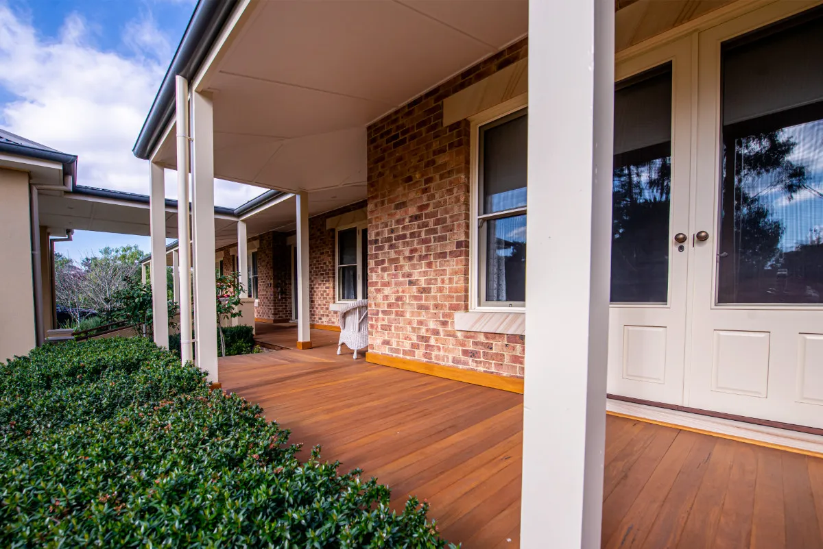 Side verandah of the Warranwood home with timber decking, brick walls, and French doors.