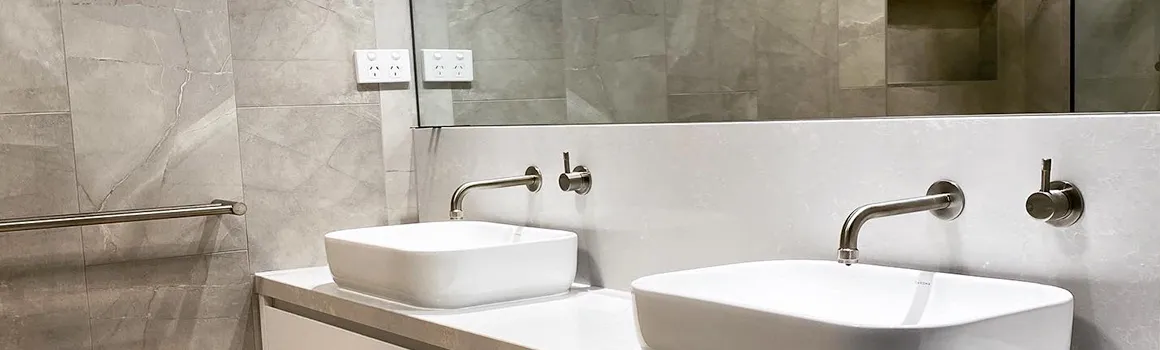 Renovated bathroom with twin white vessel basins, brushed-nickel tapware, and large-format stone-look wall tiles.